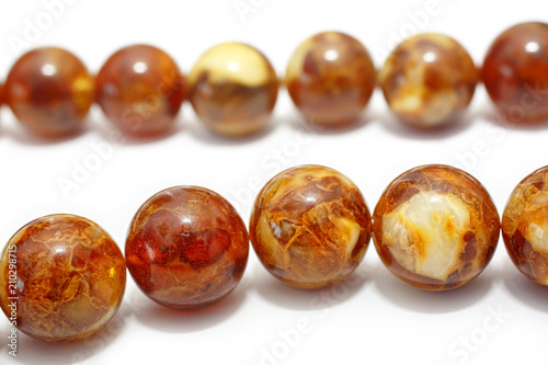 Amber. Beads made from natural yellow brown amber mineral on a white background. Fashionable jewelry amber beads from round and oblong beads. Sun stone as a jeweler raw material. Frozen Resin Fossil
