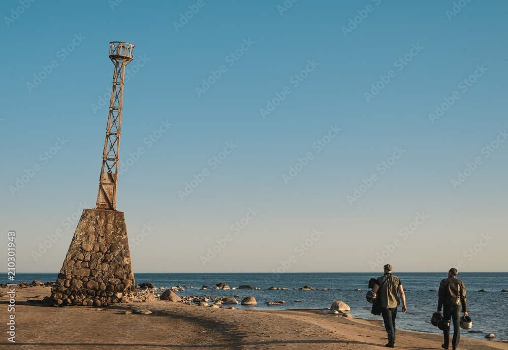 people walking along the seaside with old lighthouse people walking along the seaside with old lighthouse