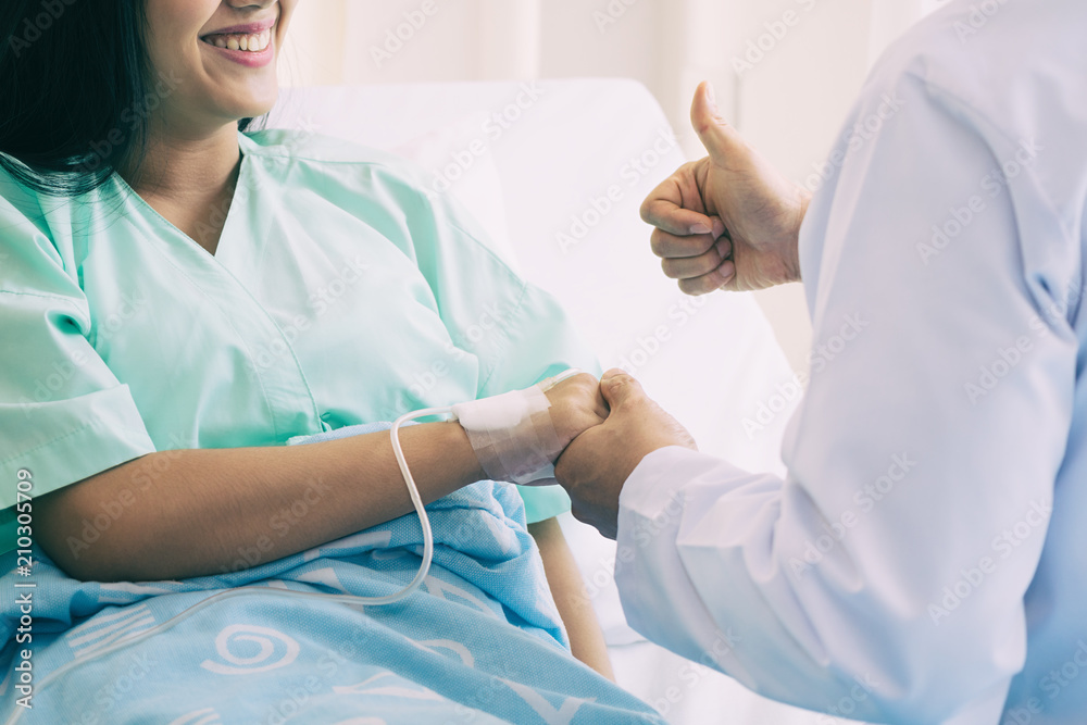 Hand of man doctor reassuring his female patient with thump up in bed at hospital. Medical ethics and trust concept.. Hand of man doctor reassuring his female patient with thump up in bed at hospital. Medical ethics and trust concept..