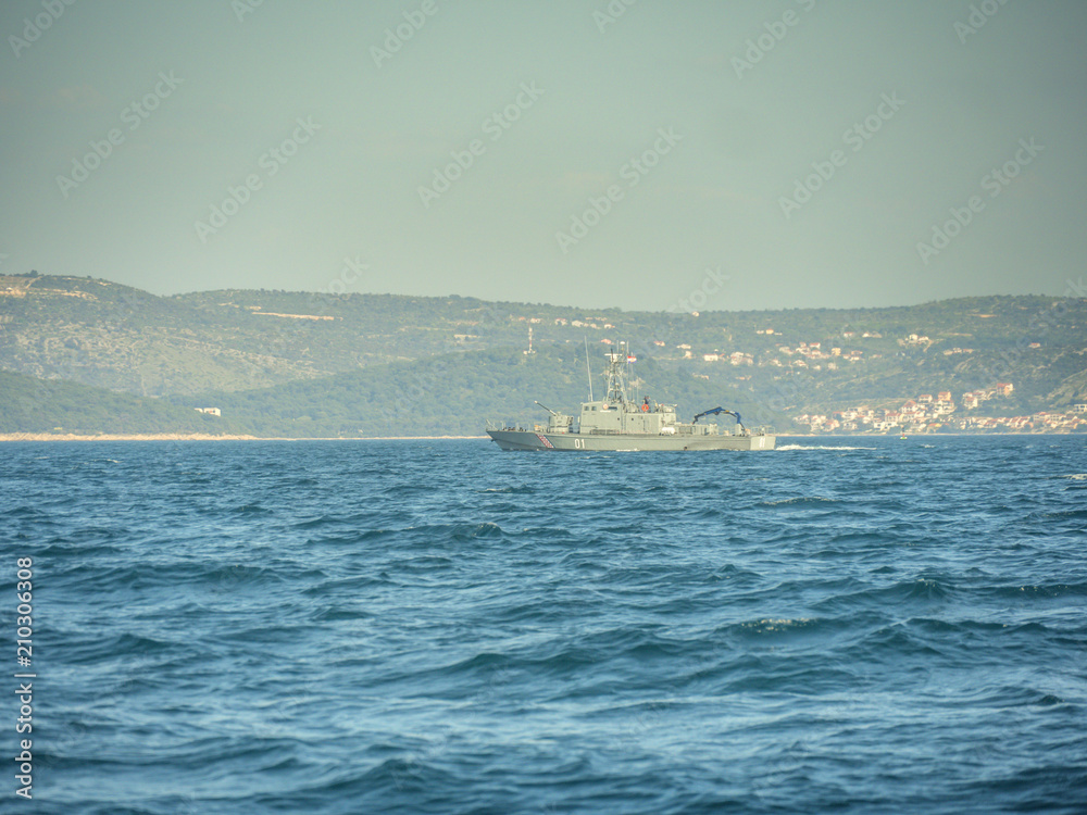 Croatian military battleship cruising arround at evening sunset.