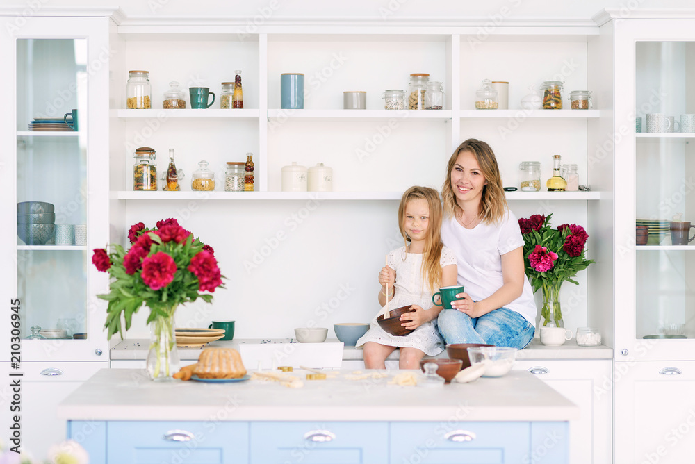 Mom and her little daughter are sitting in a big bright kitchen and preparing a healthy breakfast Mom and her little daughter are sitting in a big bright kitchen and preparing a healthy breakfast