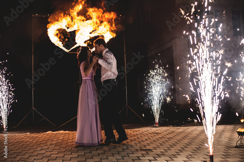 Young groom and bride with two burning hearts fireshow at night, wedding or marriage concept.