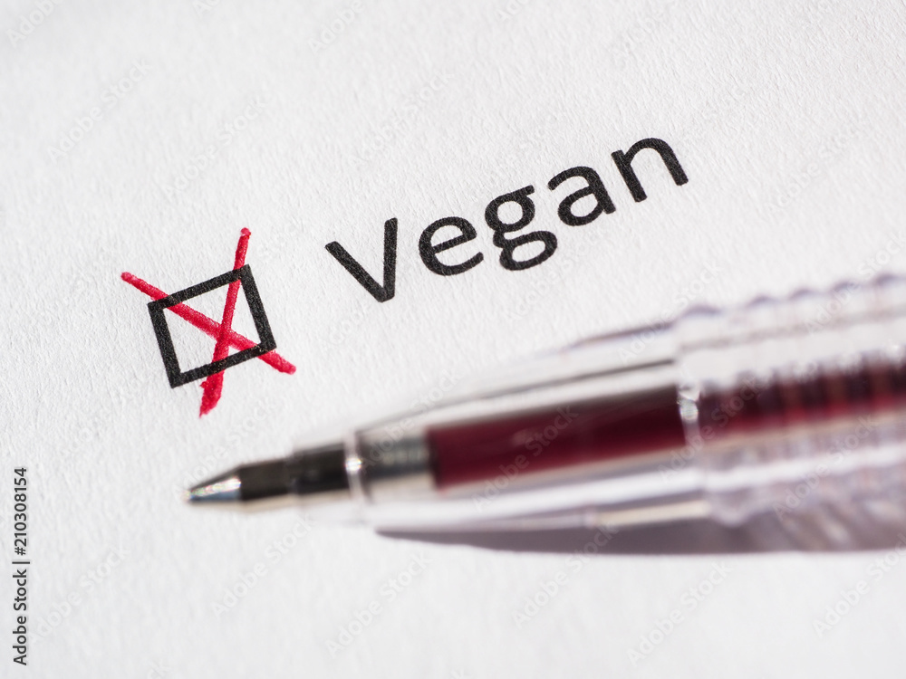 Questionnaire. Red pen and the inscription VEGAN with check mark on the white paper. Close-up background. High-quality macro photography. Questionnaire. Red pen and the inscription VEGAN with check mark on the white paper. Close-up background. High-quality macro photography.