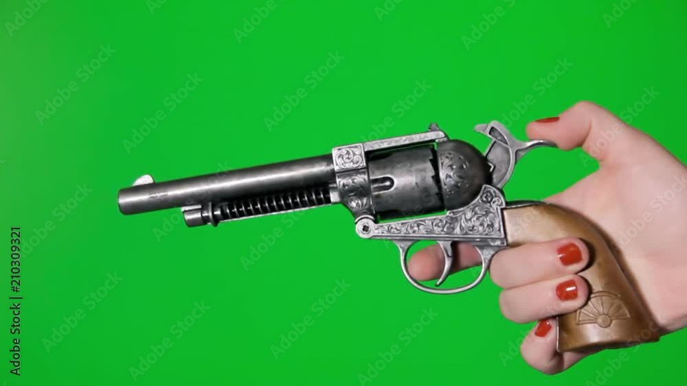 A female hand holding a revolver gun appearing and shooting. Green background.
