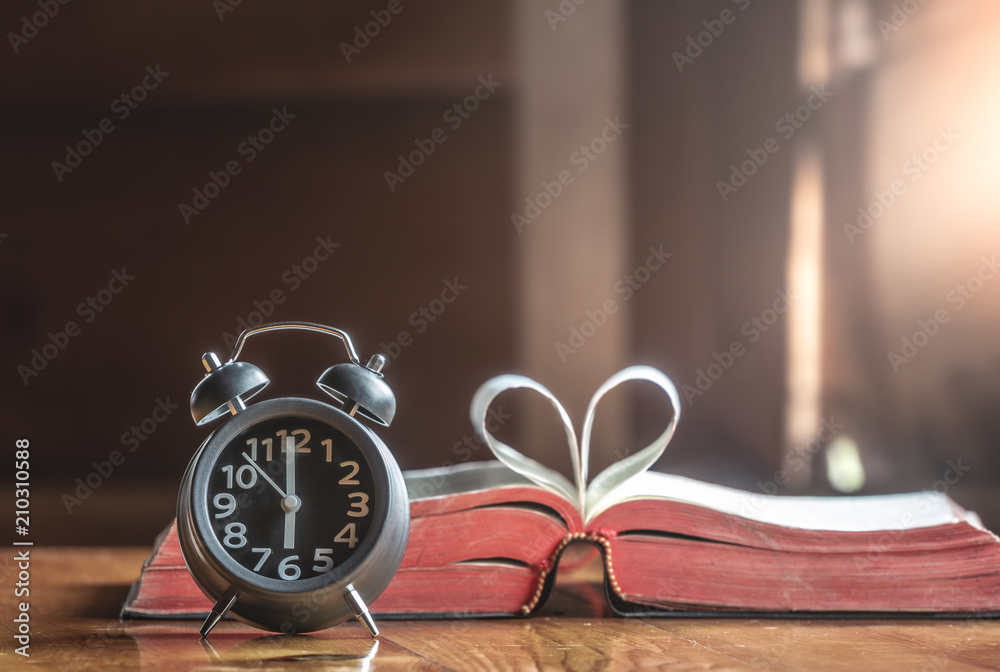 Clock on wooden table with Bible background, How much the time of man given to God,christian concept. Clock on wooden table with Bible background, How much the time of man given to God,christian concept.