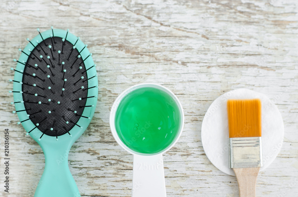 Hair brush and small scoop with green gel hair mask (conditioner) with  spirulina, aloe vera and marine collagen extracts. Spa and natural skin and  hair care concept. Top view, copy space. Stock