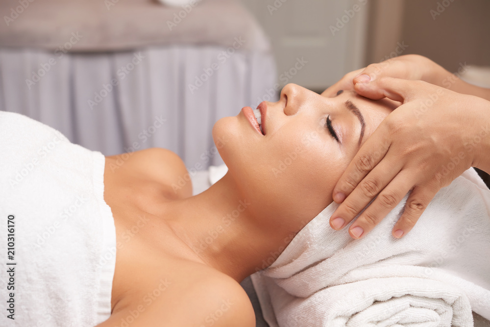 Calm female taking pleasure in relaxing massage on her face in spa salon Calm female taking pleasure in relaxing massage on her face in spa salon