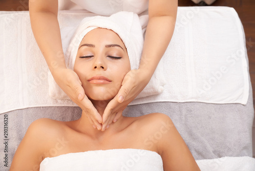 View of young relaxed female having facial massage for skin rejuvenation