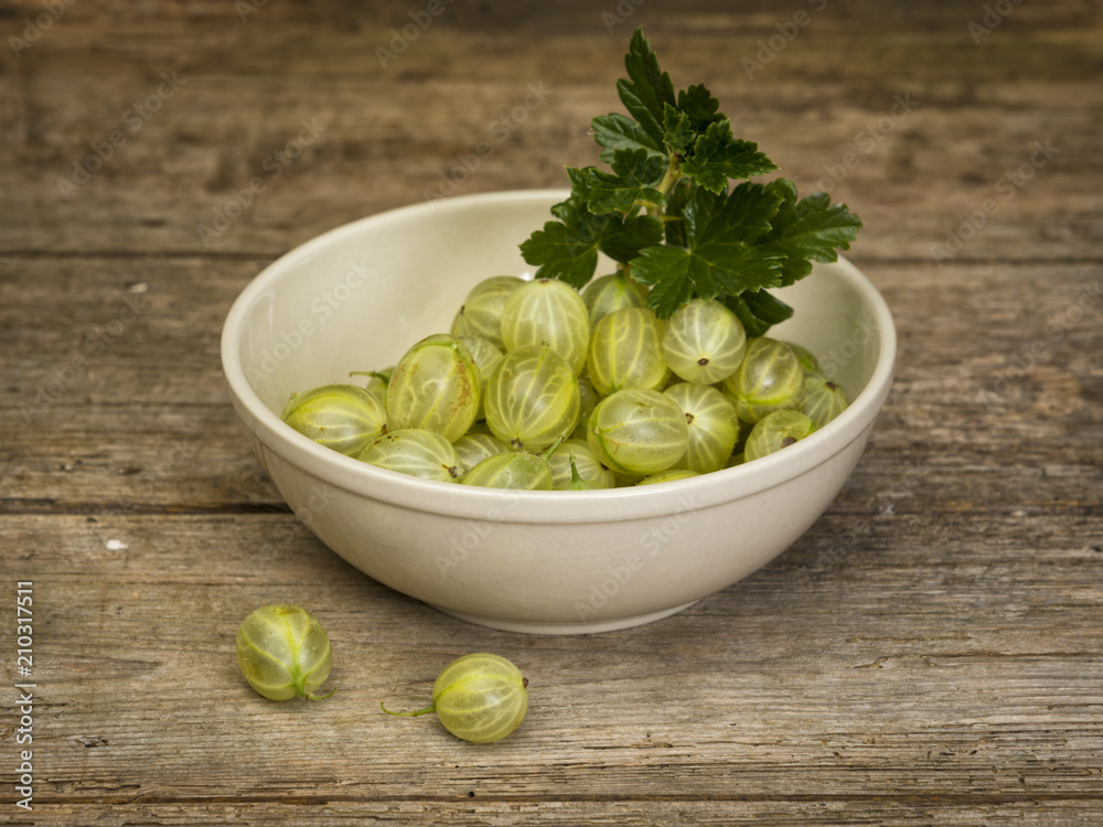 Gooseberries in a bowl on rustic wooden table Gooseberries in a bowl on rustic wooden table
