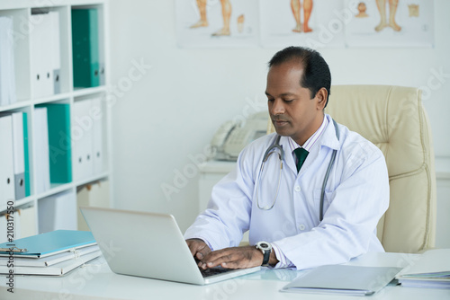 Serious Indian doctor using his laptop for work