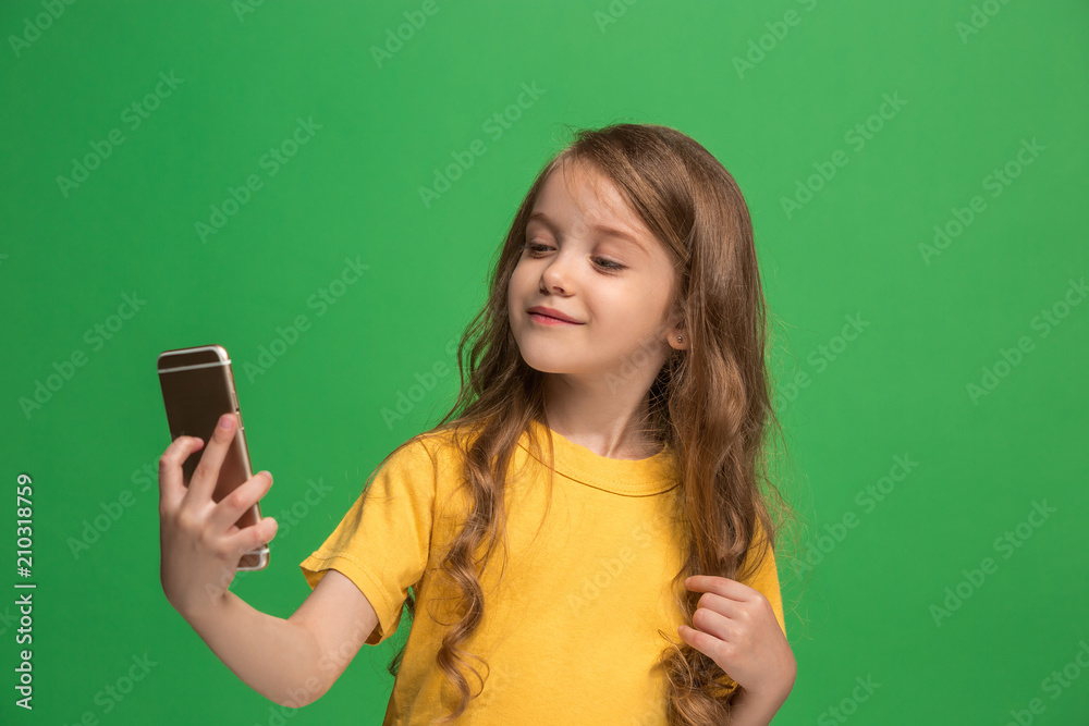 The happy teen girl standing and smiling against green background.