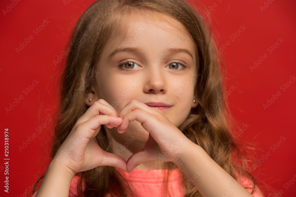 The happy teen girl standing and smiling against red background. The happy teen girl standing and smiling against red background.
