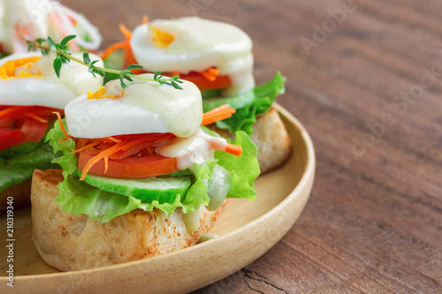 Open faced sandwich with toast and fresh vegetable and boil egg top with salad dressing or mayonnaise on wooden plate. Delicious breakfast for family on wood table. Homemade and healthy food concept.