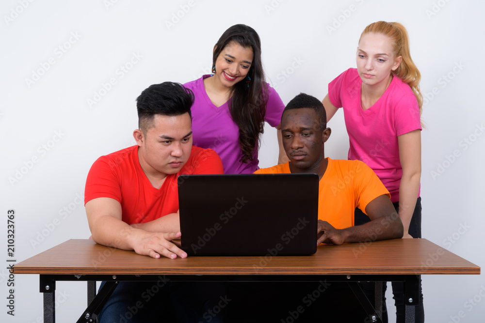 Studio shot of diverse group of multi ethnic friends using lapto Studio shot of diverse group of multi ethnic friends using lapto
