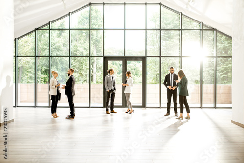 Business people at the spacious modern hall with big window overlooking on the park. Wide view with copy space