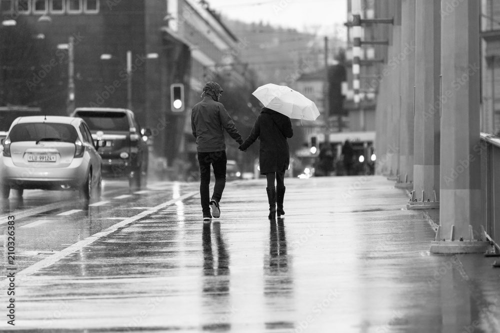 Couple holding hands in the rain with umbrellas 