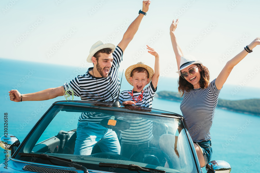 Obraz premium Happy family travel by car to the sea. People having fun in cabriolet. Summer vacation concept