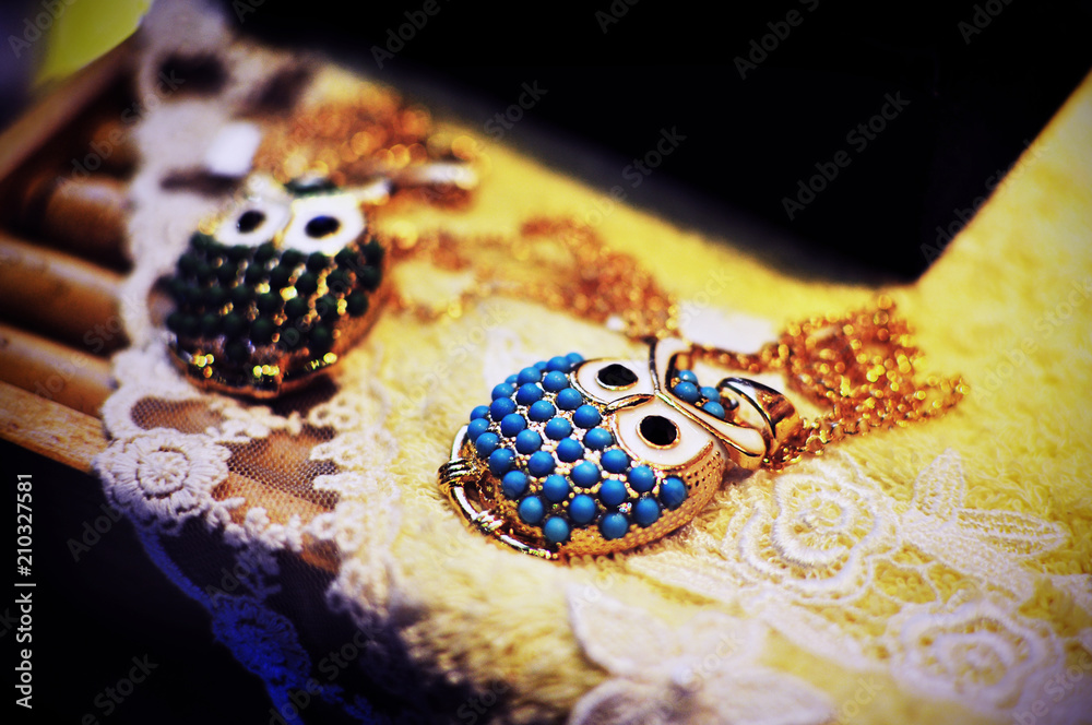 Fototapeta premium Fashion owl necklace with gemstones for sale on a piece of lace