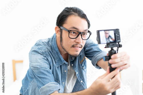 Young Asian blogger setting camera video with recording filming at home photo