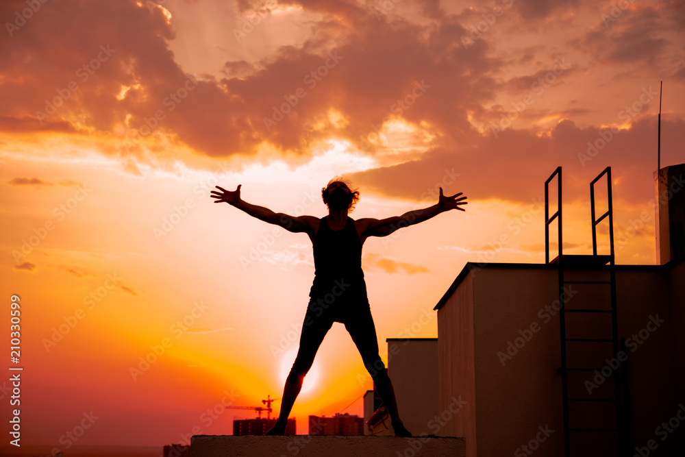Fototapeta premium A middle-aged man is engaged in yoga on the roof.