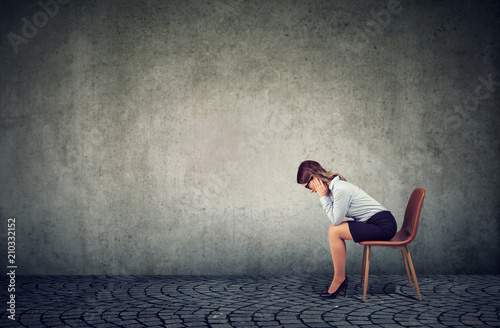 Fotografie Depressed business woman sitting on chair and looking down