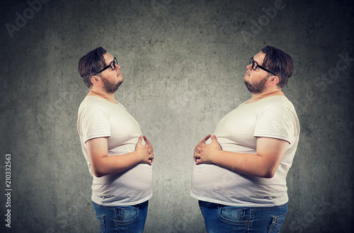 Bild auf Leinwand Young chubby man looking at fat himself feeling bloated.