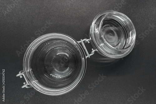 Open glass jar with metal holder on black background surface