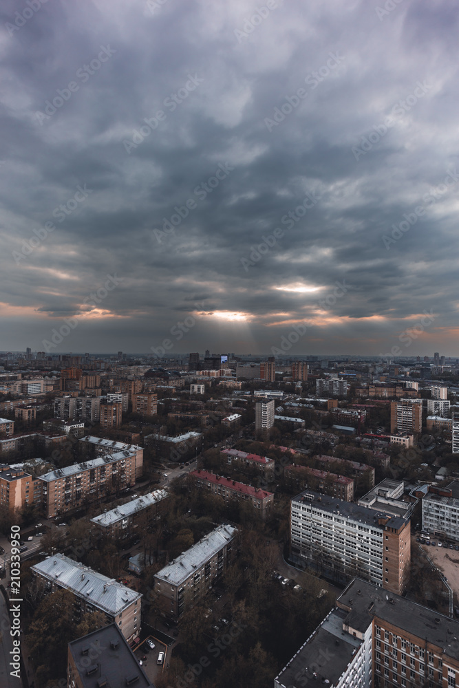Vertical shot from a high point of a dark cityscape with the blocks of flats mass built-up and a thunder sky; view from high above of urban landscape with the residential neighborhood and overcast sky