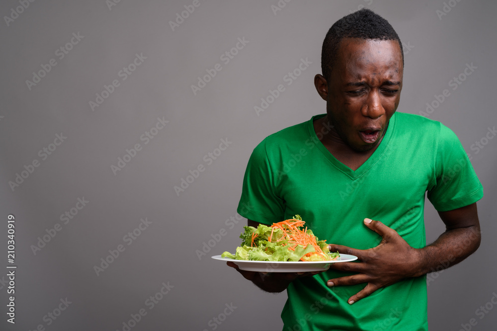 Young African man wearing green shirt against gray background Young African man wearing green shirt against gray background