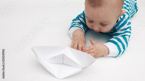 Funny baby plays with paper boat photo