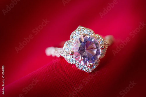Jewelry luxury pink gold ring with sapphire gemstone on red fabric texture background © Kwangmoozaa