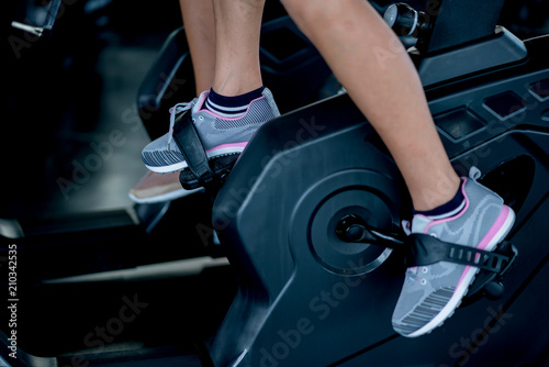 close up woman feet ride bicycle machine in gym health ideas concept