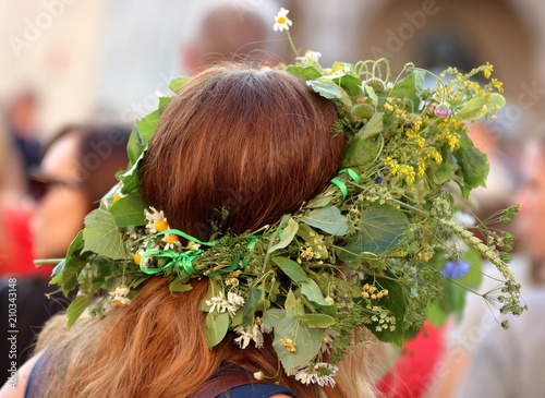 Głowa rudowłosej kobiety w kwietnym wianku na głowie, tradycja nocy świętojańskiej, tradycja ludowa
