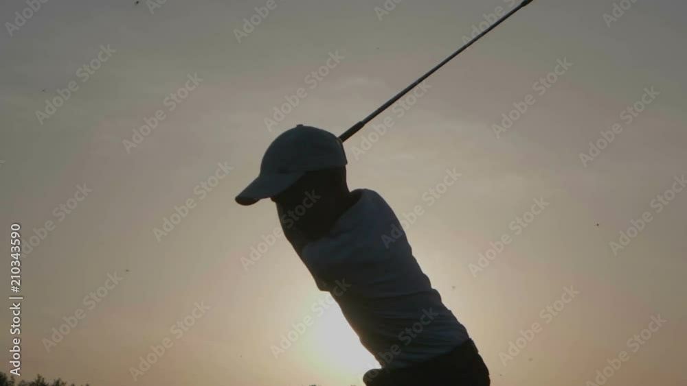 Silhouette of boy golfer with golf bag at sunset