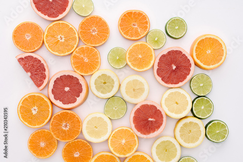 top view of various citrus fruits slices spilled on white surface