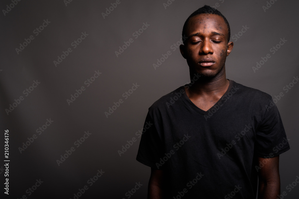 Young African man wearing black shirt against gray background Young African man wearing black shirt against gray background