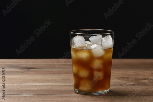 Vaso de café con hielo sobre mesa de madera