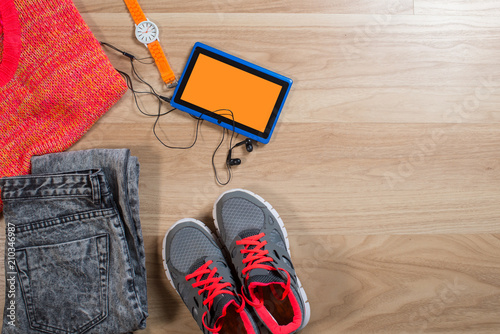 A tablet with some clothes and acessories flatlay on wooden background