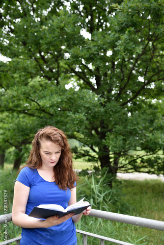 Vertical shot of student reading a book in a park