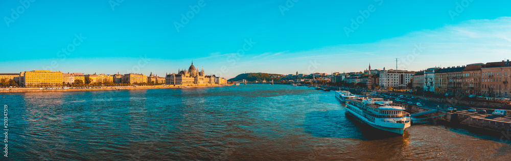 big panorama of budapest at danube river with an touristic ship in the foreground and parliament of hungary in the background