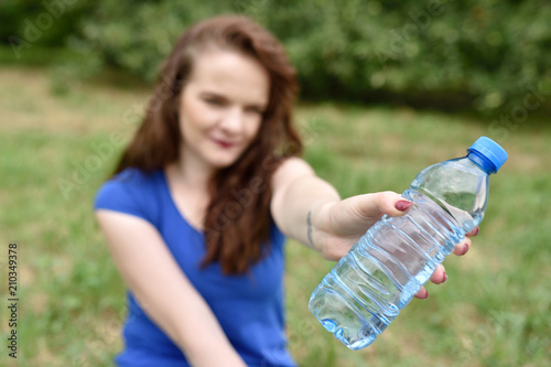 Casual woman holding a bottle of water sitting in a park