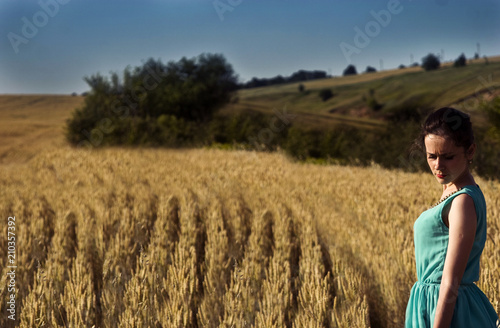 A girl in a blue dress on a golden wheat field