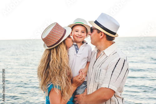 Happy family on vacation. Mom, Dad and little son stand on the beach. A traveling family. Kisses, smiles. © александр таланцев