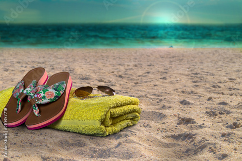 Handtuch, Flip Flops und Sonnenbrille am Strand. Sonnenuntergang am Abend.