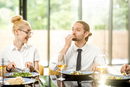 Beautiful couple having business lunch with delicious meals and wine at the restaurant