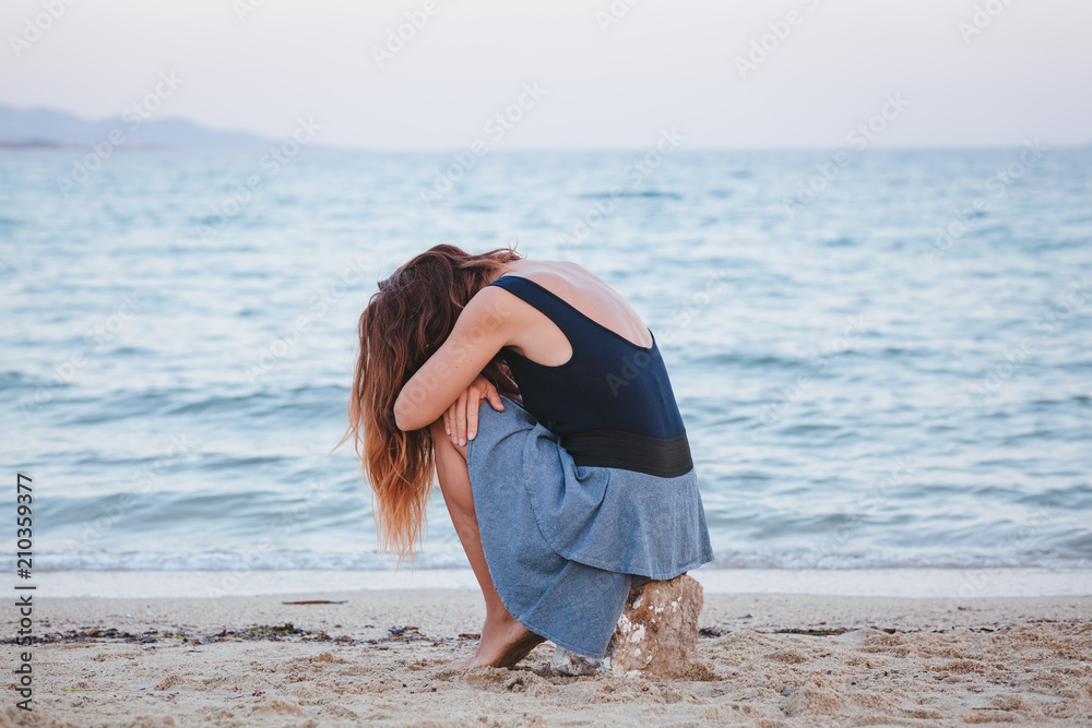 Woman alone and depressed sitting at the beach