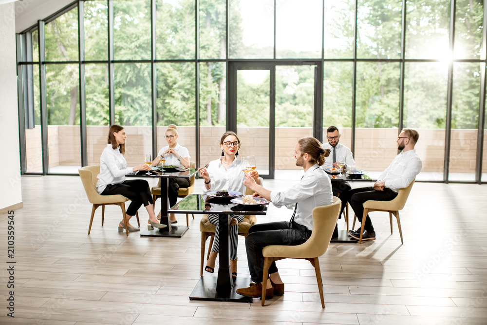 Obraz premium Business people having lunch with delicious meals sitting in pairs at the modern restaurant