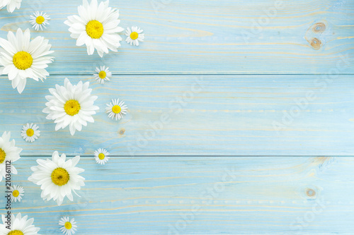 White daisies and garden flowers on a light blue worn wooden table. The flowers are arranged side, empty space left on the other side. photo