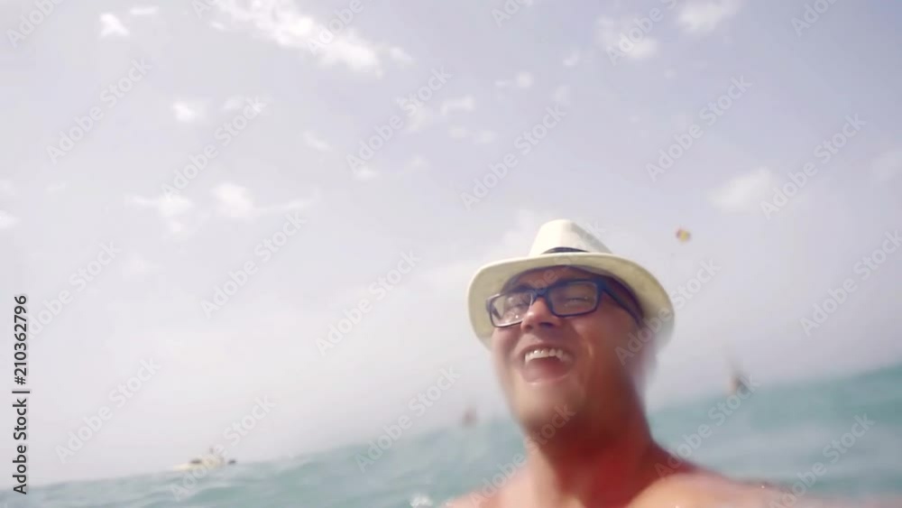 portrait of a happy and adult man in a hat who sunbathes in the sun in the cool sea portrait of a happy and adult man in a hat who sunbathes in the sun in the cool sea