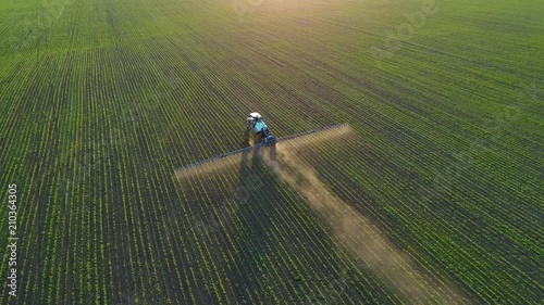 4K aerial drone footage. Following tractor sprayer on soybean fields at sunset